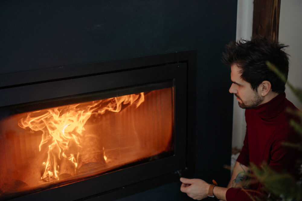 Man in red long sleeves sitting near a fireplace